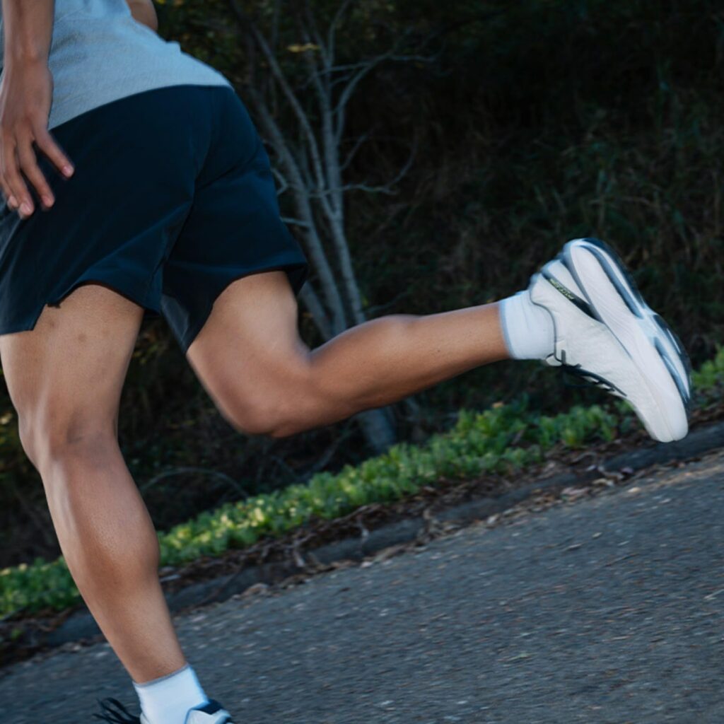 Vue en action d'un coureur sur route portant les Topo Athletic Atmos, un modèle recommandé comme chaussure de running pour coureur lourd et pieds larges grâce à son amorti maximal et son espace pour les orteils